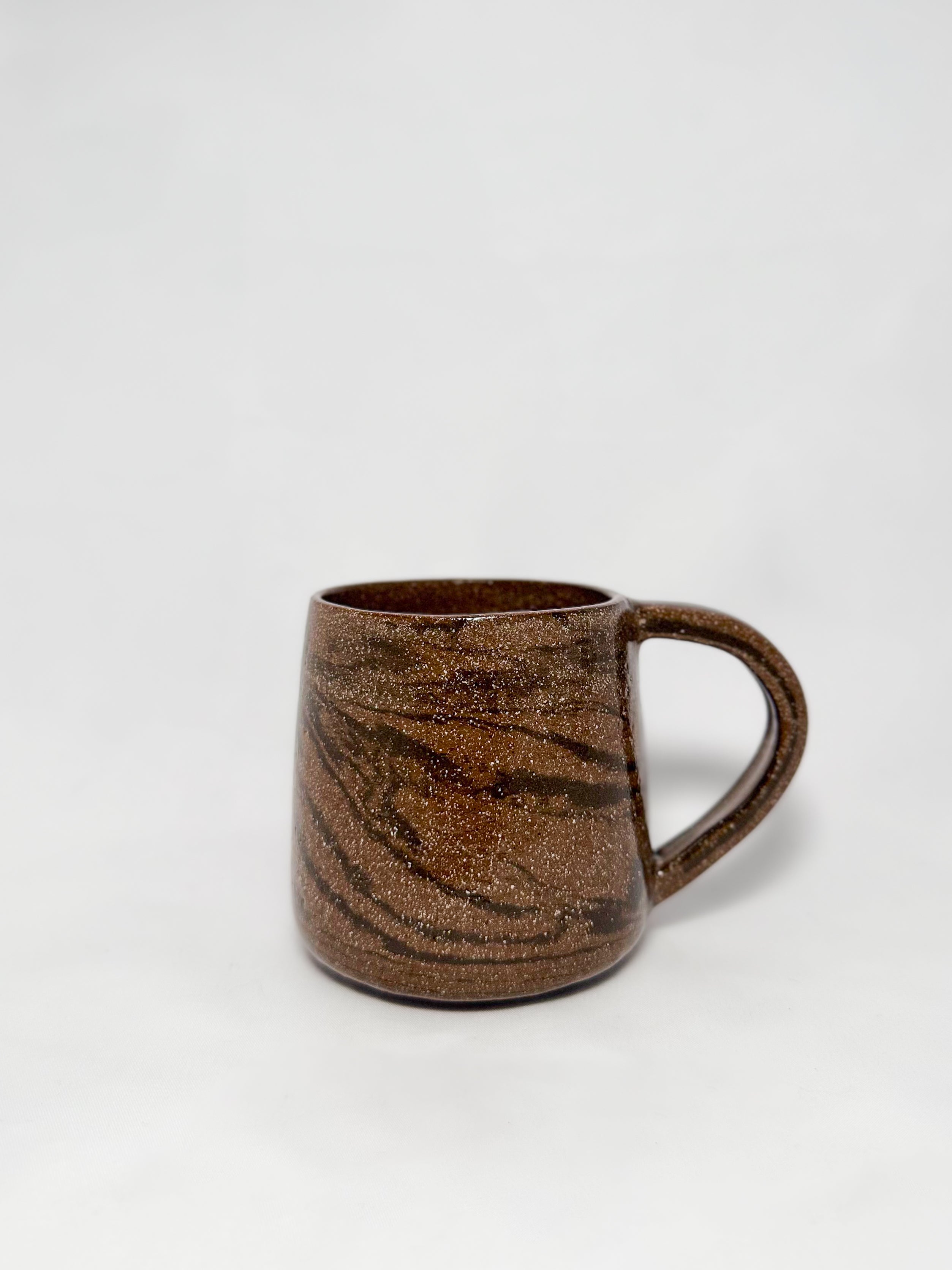 A brown marbled stoneware mug with swirls of light brown and dark brown clay