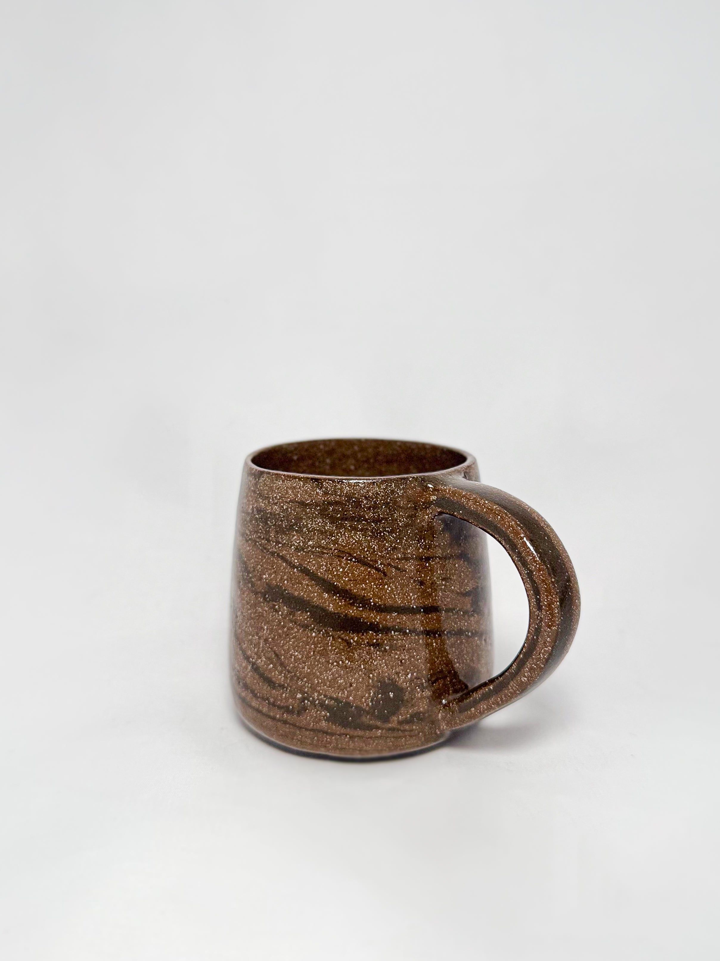 A brown marbled stoneware mug with swirls of light brown and dark brown clay