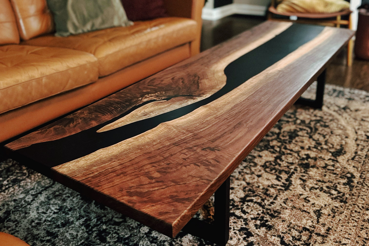Custom walnut epoxy river table, displayed in a living room with black epoxy and metal legs. Made in Covington, Kentucky. 