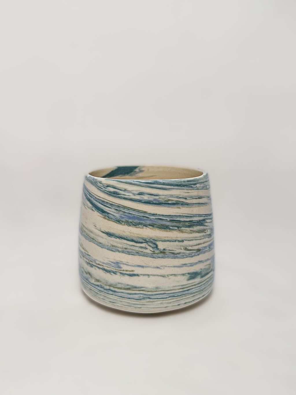 A blue and white marbled stoneware mug showing detailed unique swirls of blue and green clay