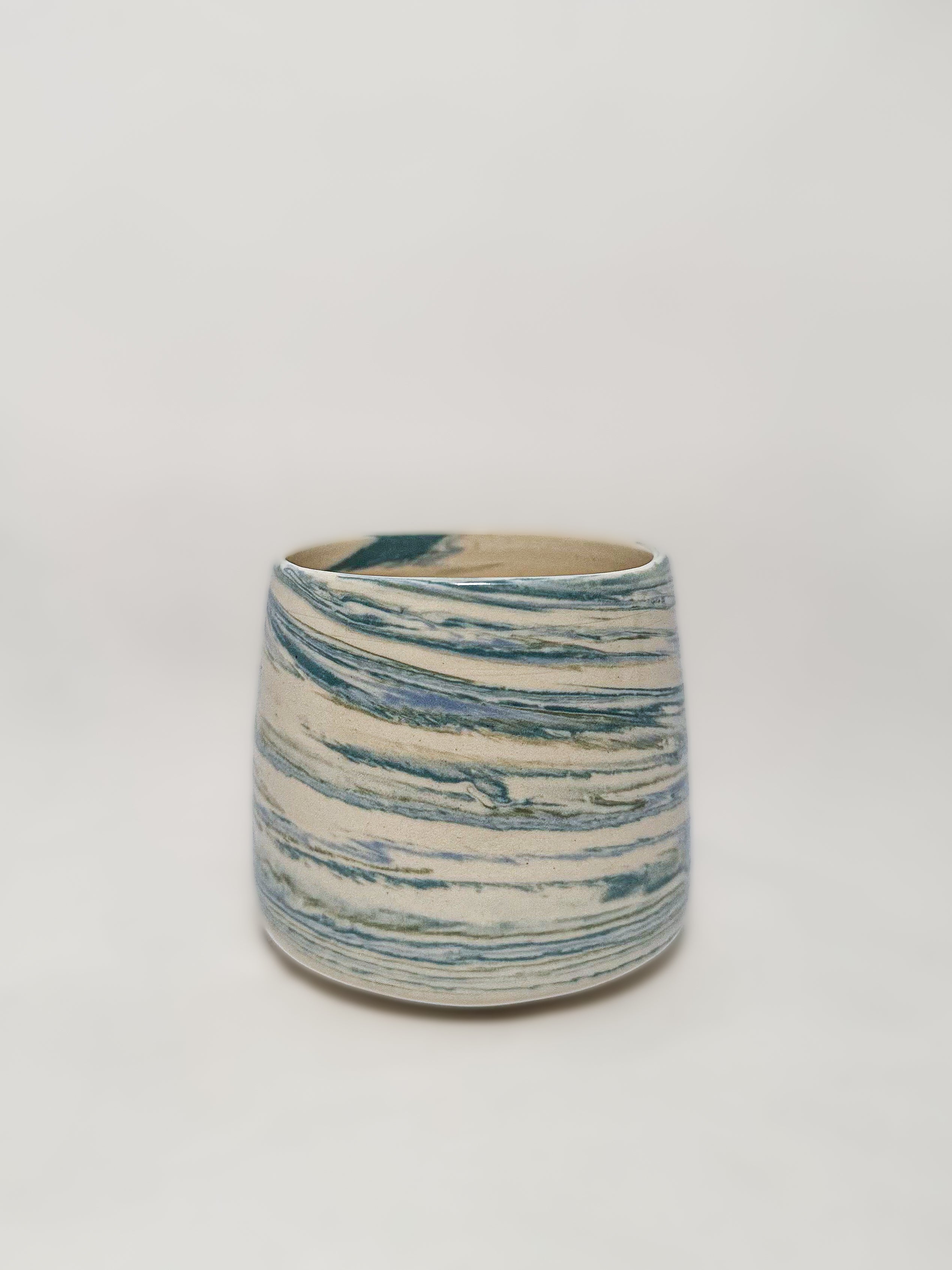 A blue and white marbled stoneware mug showing detailed unique swirls of blue and green clay