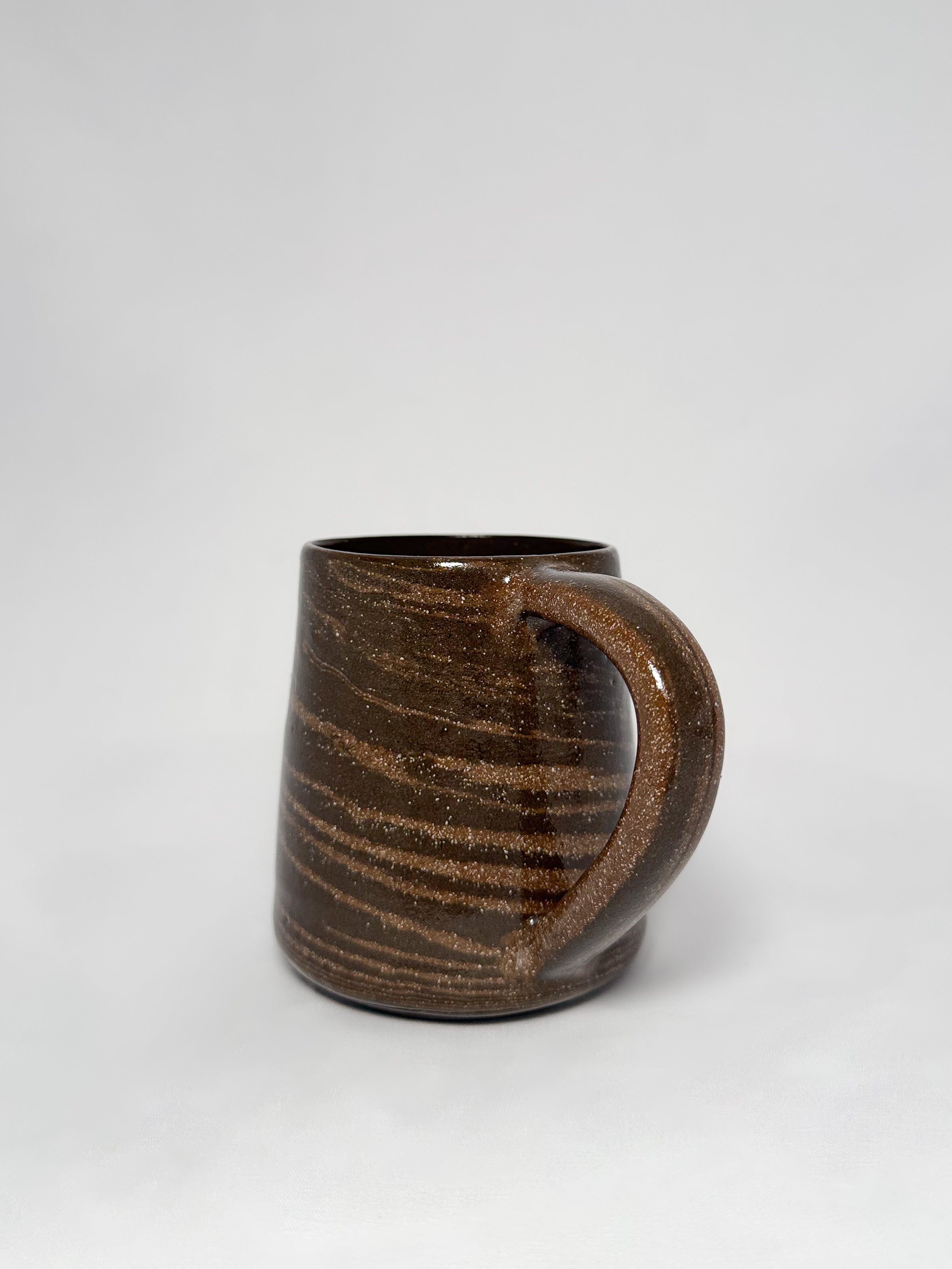 A brown marbled stoneware mug with swirls of light brown and dark brown clay