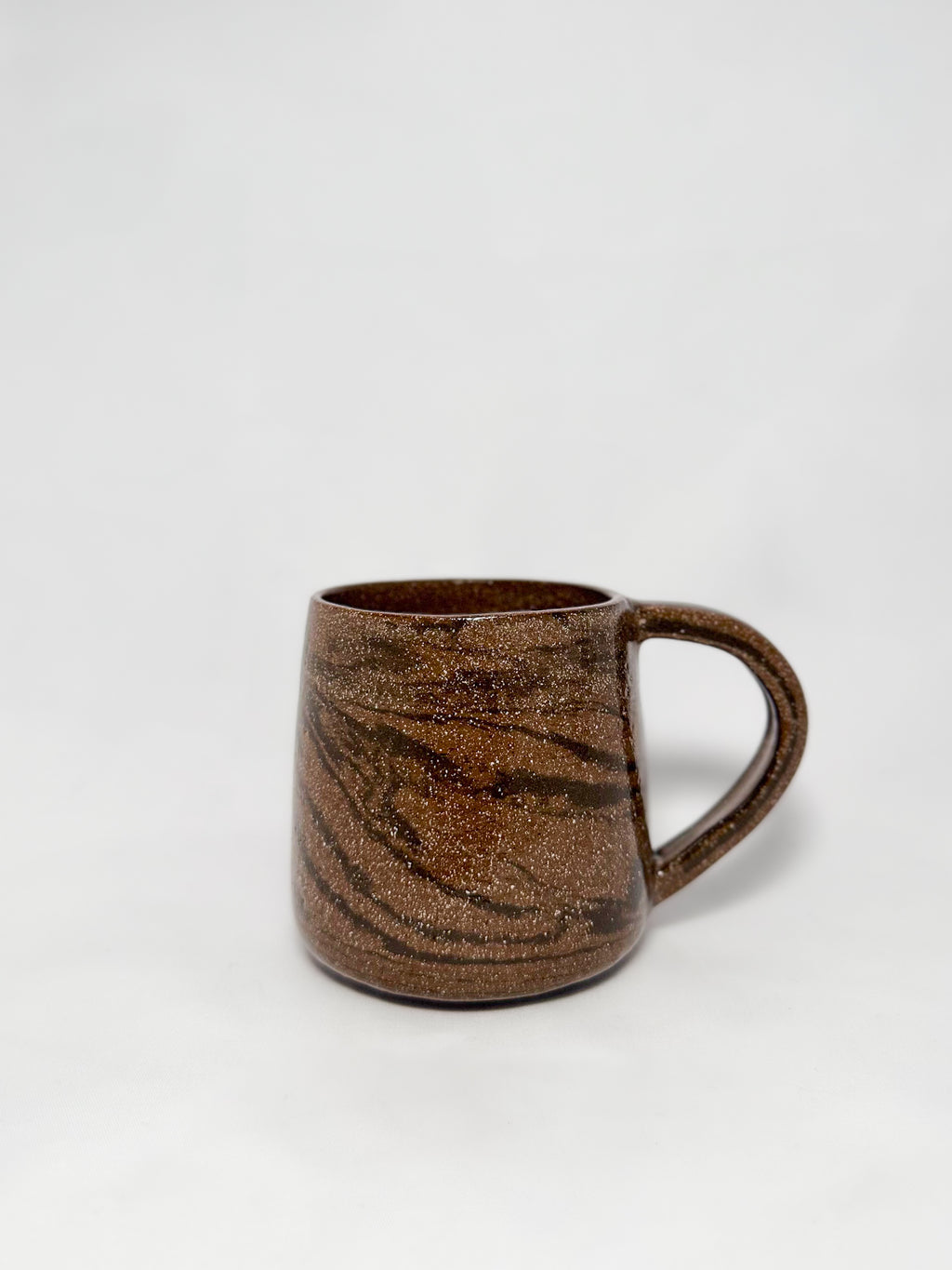 A brown marbled stoneware mug with swirls of light brown and dark brown clay