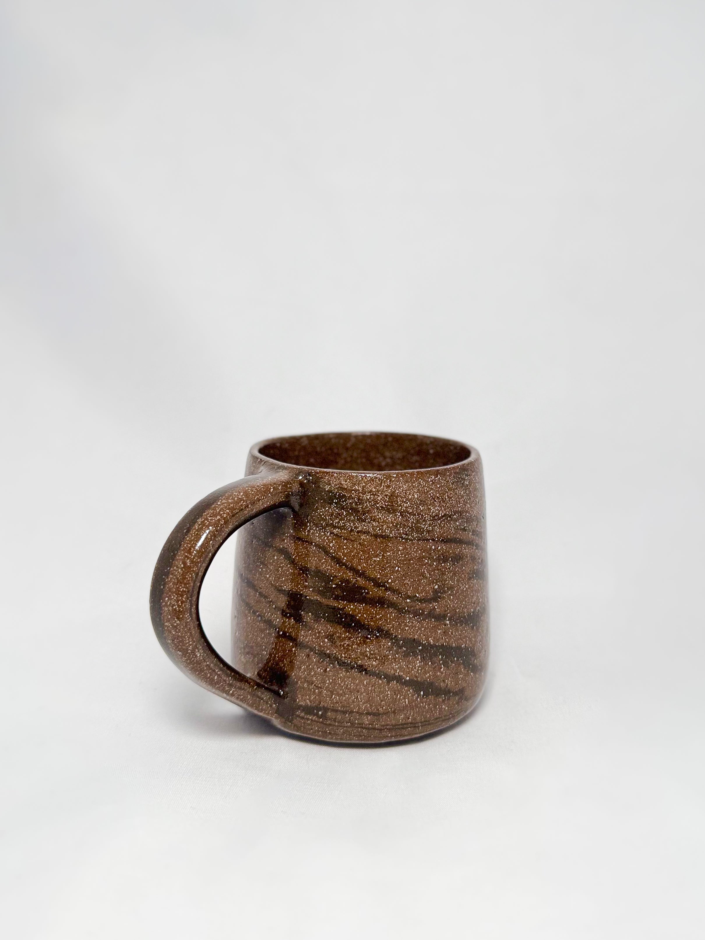 A brown marbled stoneware mug with swirls of light brown and dark brown clay