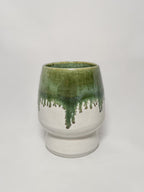 A ceramic stoneware vase with mossy green glaze dripping down into a white glaze