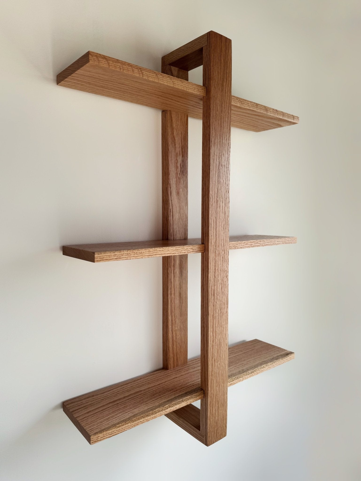 The Odyssey floating oak shelf with a modern bracket, a handcrafted wall-mounted storage solution.