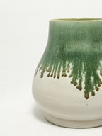 A ceramic stoneware vase with mossy green glaze dripping down into a white glaze