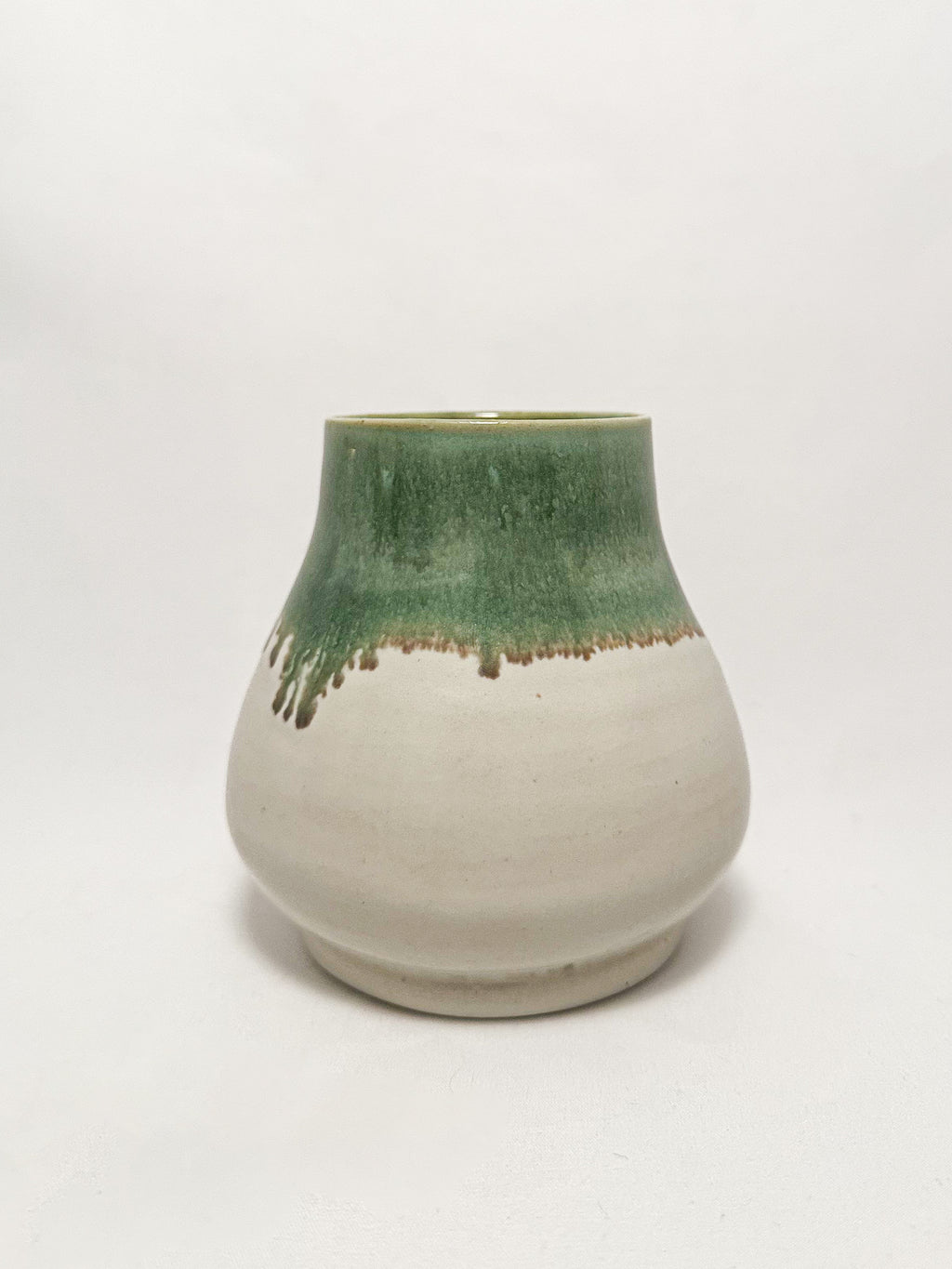 A ceramic stoneware vase with mossy green glaze dripping down into a white glaze